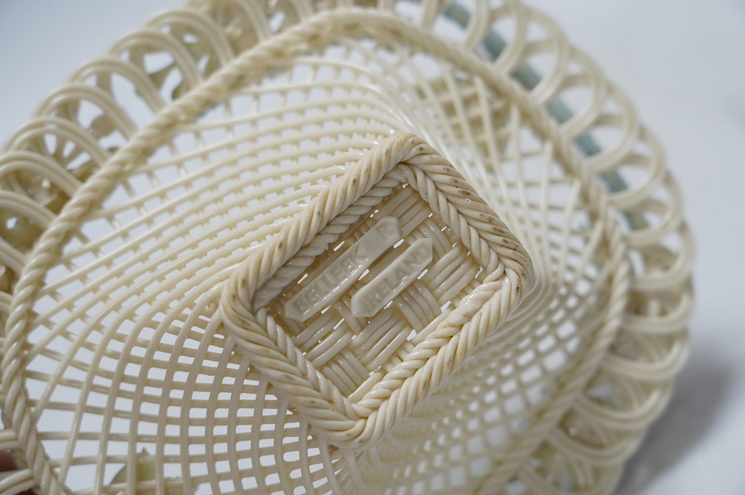 Three 20th century Belleek items with applied floral decorations; a jug, 15cm high, and two basket work dishes, largest 20cm wide. Condition - good